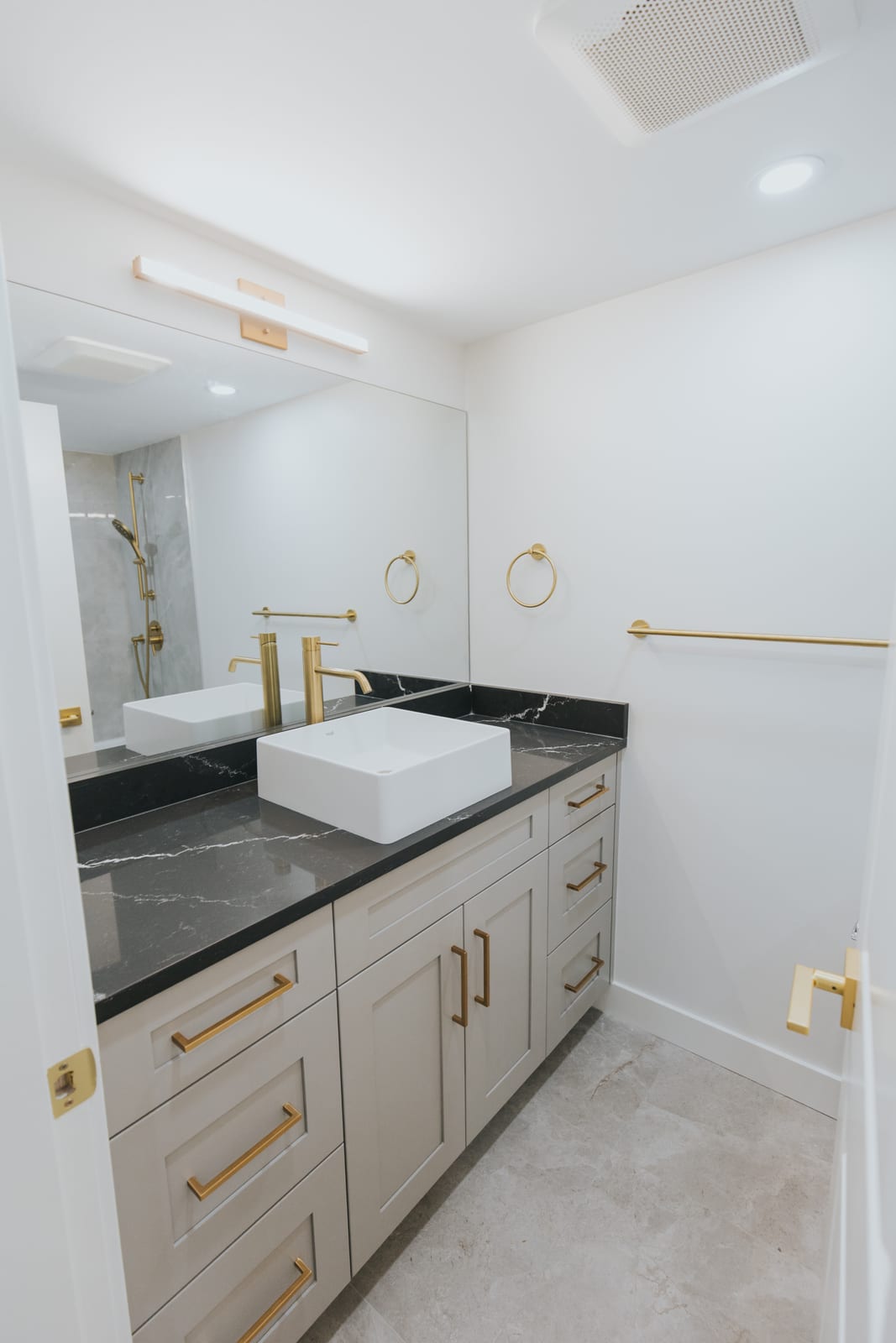 Custom bathroom vanity with vessel sink, black quartz counter, and brushed gold hardware