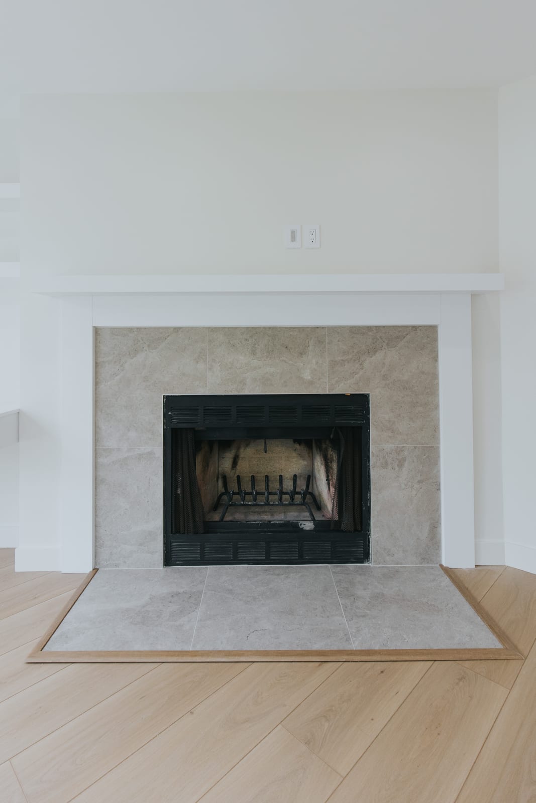 Rebuilt fireplace surround in large-format stone tile with a new hearth and white mantel